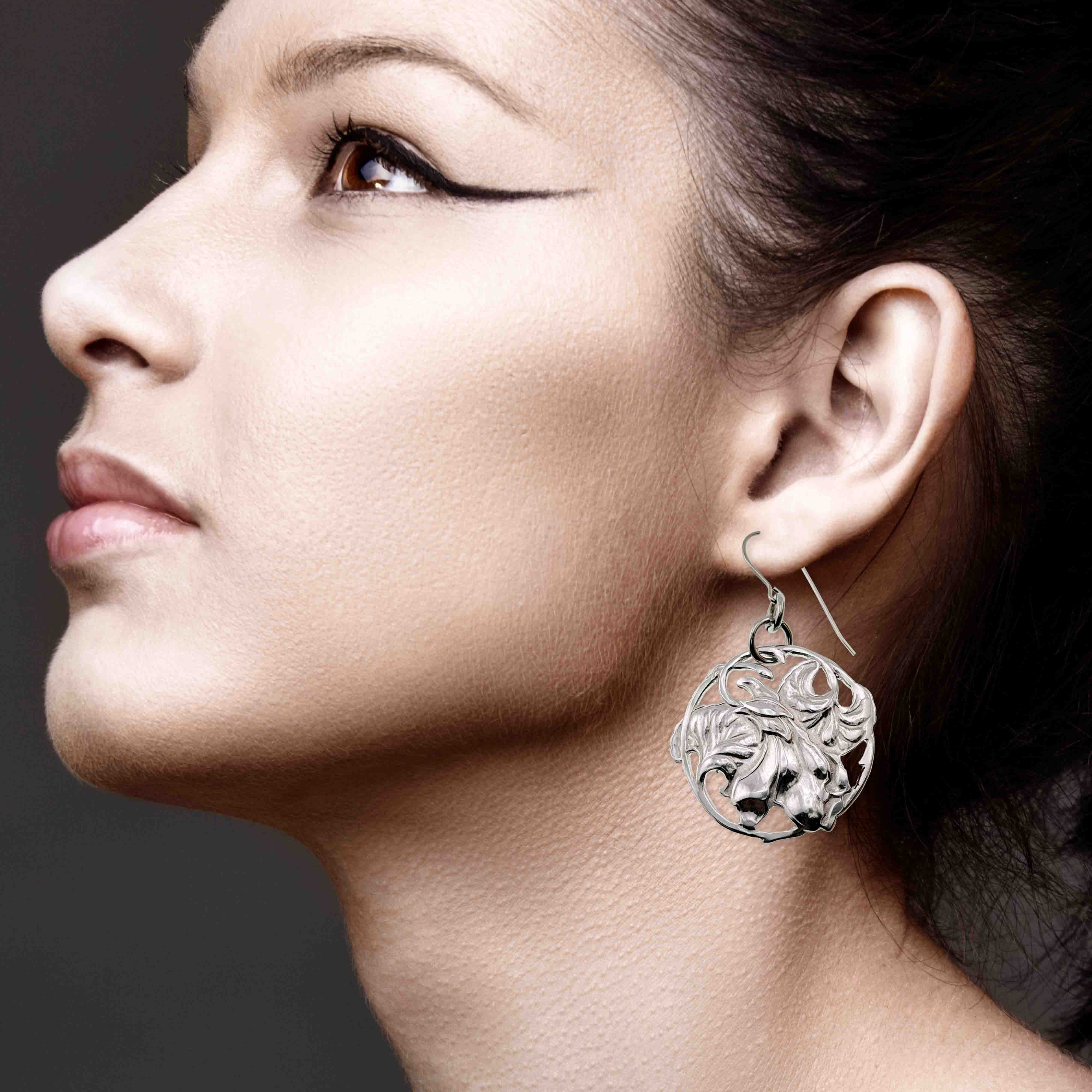 2 of 7: Close-up of a woman wearing an Art Nouveau Aluminum Lily Flower Disc Drop Earring with a dark background