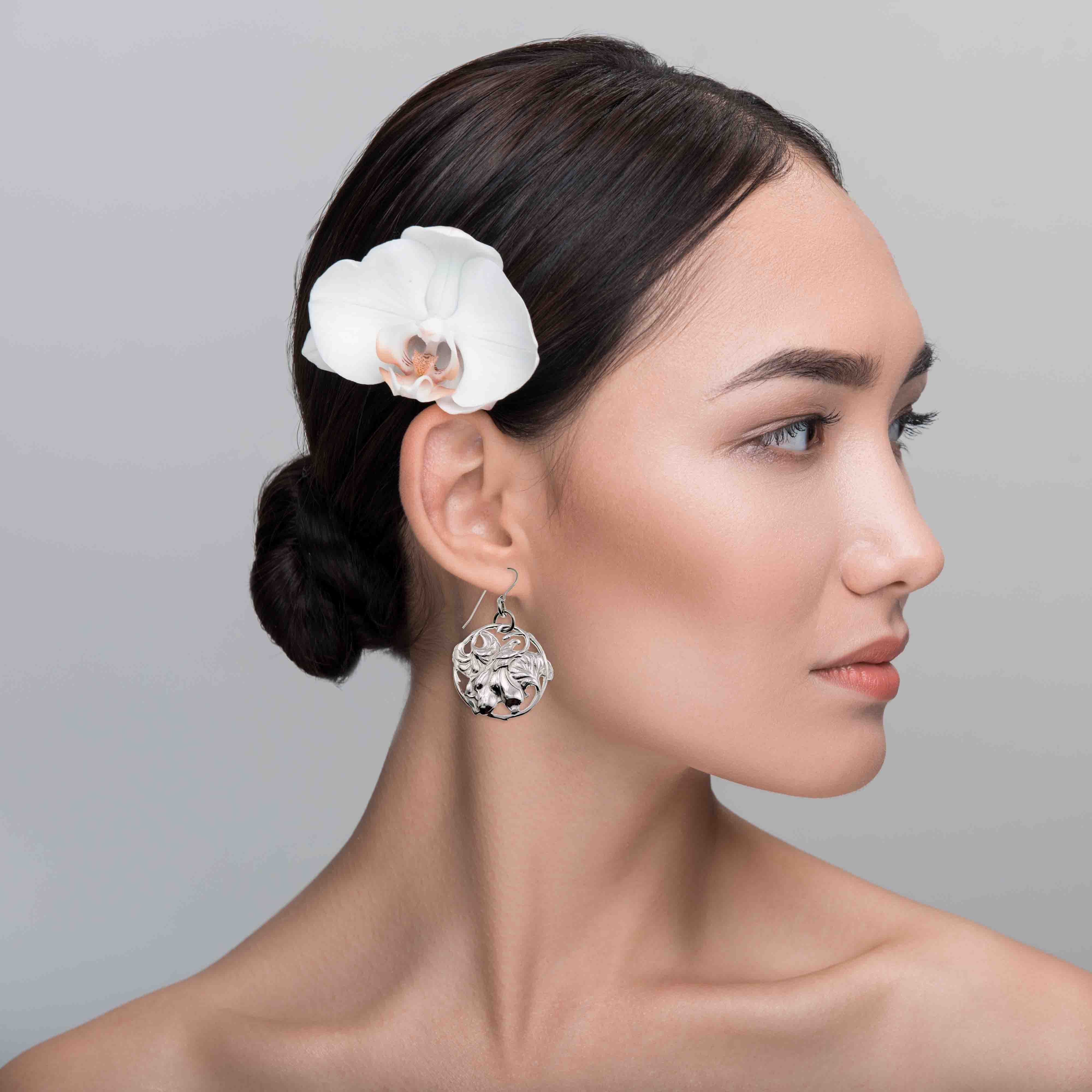 6 of 7: Woman with a white flower in her hair against a gray background wearing Art Nouveau Aluminum Lily Flower Disc Drop Earrings
