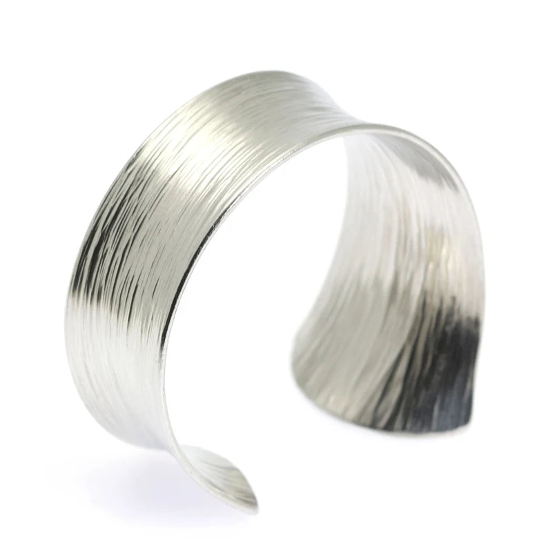 A Tapered Bark Anticlastic Aluminum Bangle Bracelet on a White Background