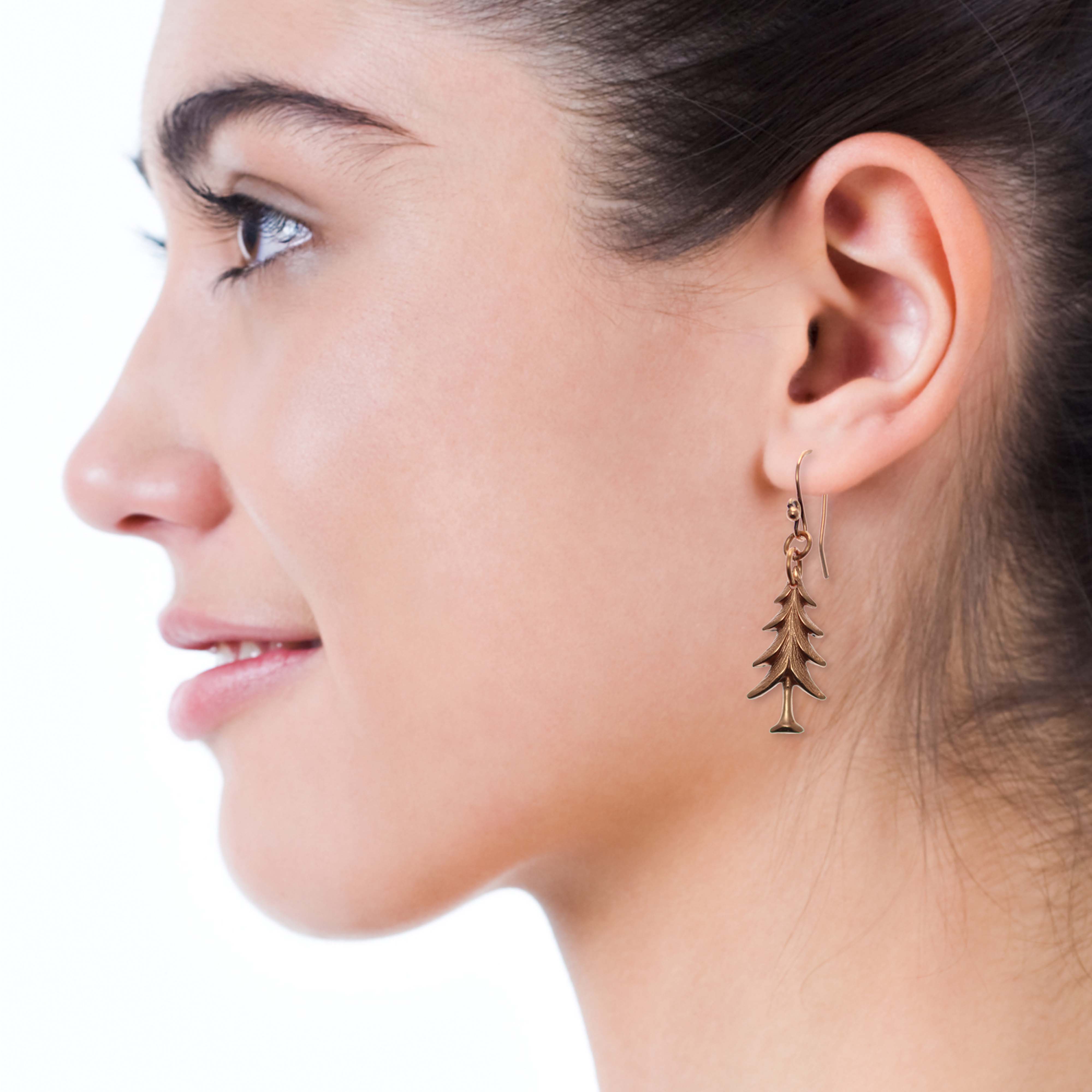 2 of 7: Close up of Christmas Tree Charm Copper Dangle Earrings on a Female Model