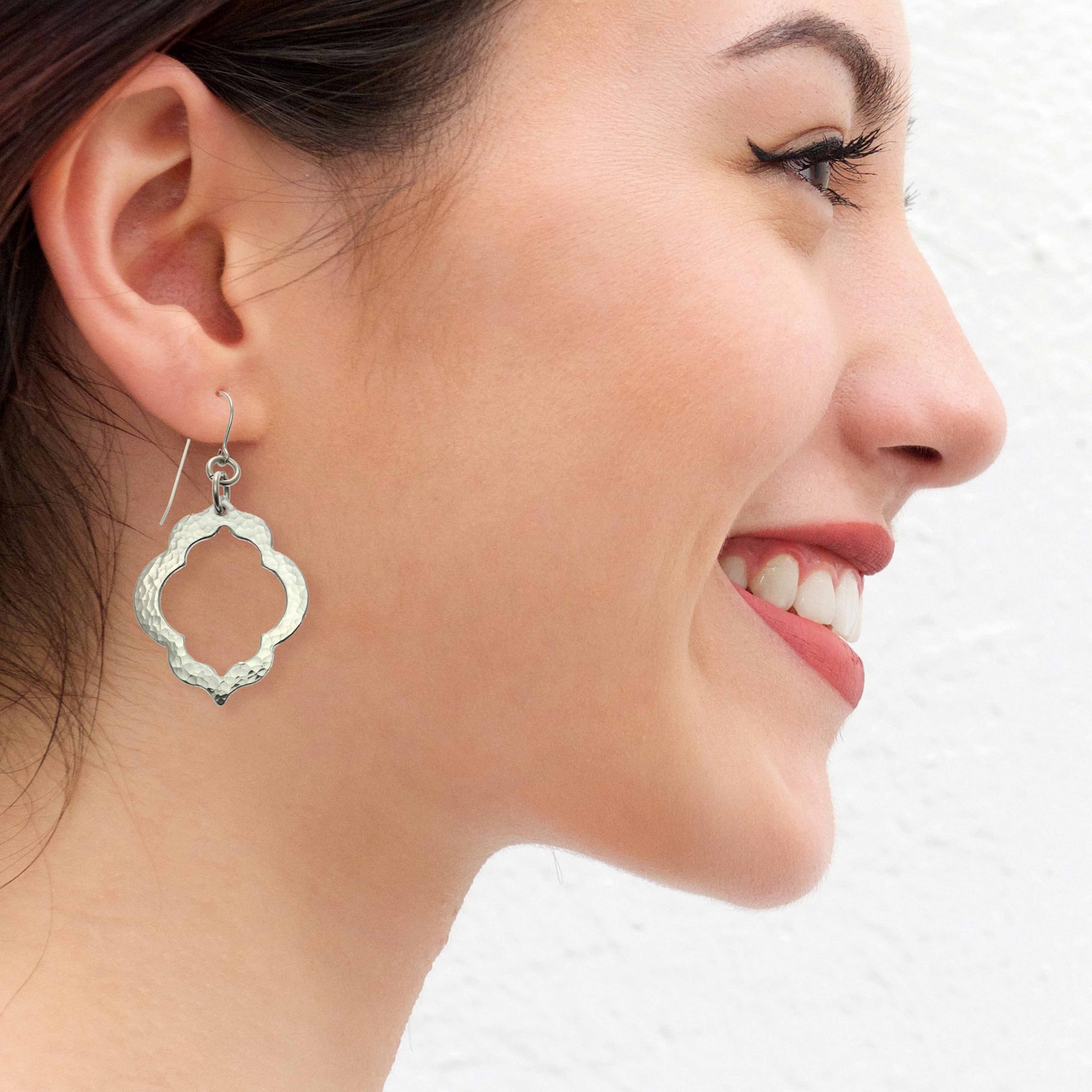 A Smiling Woman Wearing Pierced Hammered Quatrefoil Aluminum Earrings