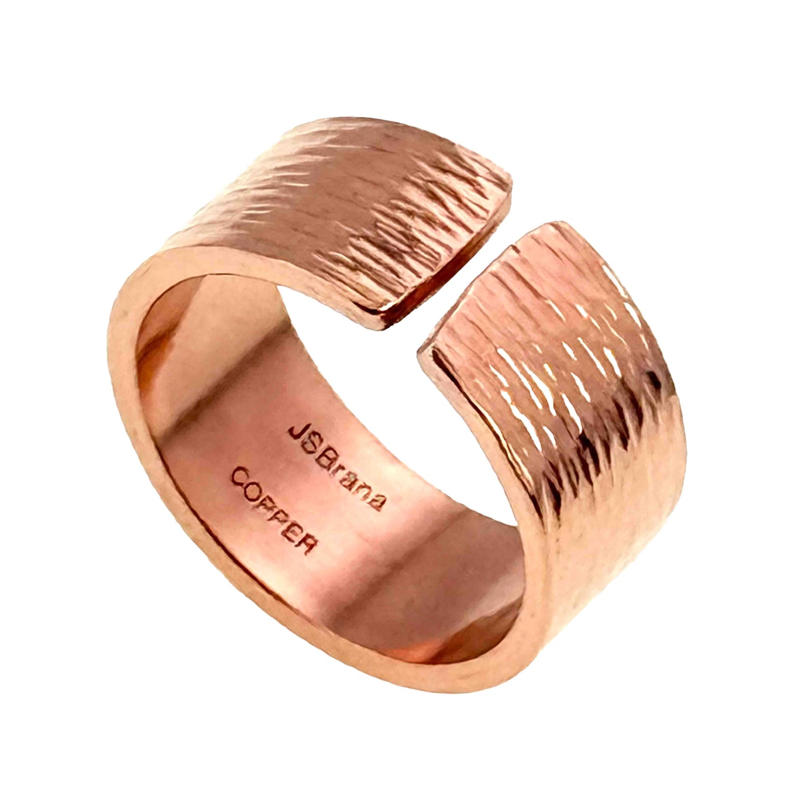 Polished 10mm open copper cuff ring with hand chased bark texture, rounded edges, warm rose copper shine, and John S. Brana Copper stamp visible inside.
