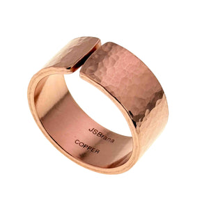 1 of 9: Handcrafted wide copper cuff ring with a hammered texture and polished finish, featuring an open adjustable design. The warm rose gold tone metal reflects light across its curved surface, with “JSBrana COPPER” stamped inside the band.