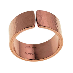 3 of 9: Wide hammered copper cuff ring with a polished finish and open front design, shown against a clean background. The ring features a smooth interior stamped with “JSBrana COPPER,” while the exterior displays a softly textured surface that reflects light in warm rose gold tones.