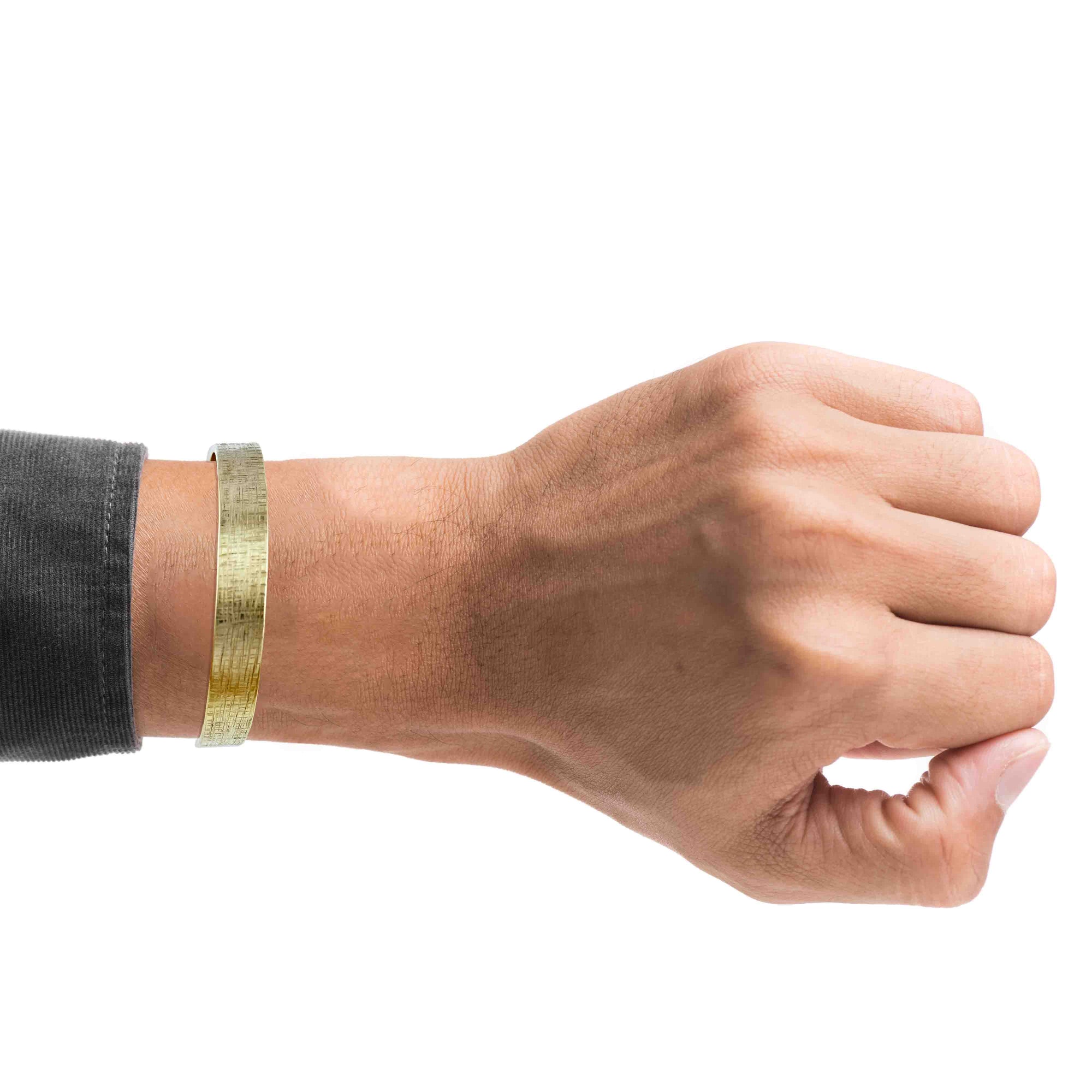 A Man's Wrist Wearing 10mm Wide Linen Nu Gold Tone Brass Cuff Bracelet on a white background