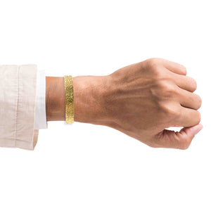 8 of 9: Model wearing a wide textured Nu Gold brass cuff bracelet on the wrist, shown against a white background to highlight the bracelet’s hammered finish, scale, and fit.