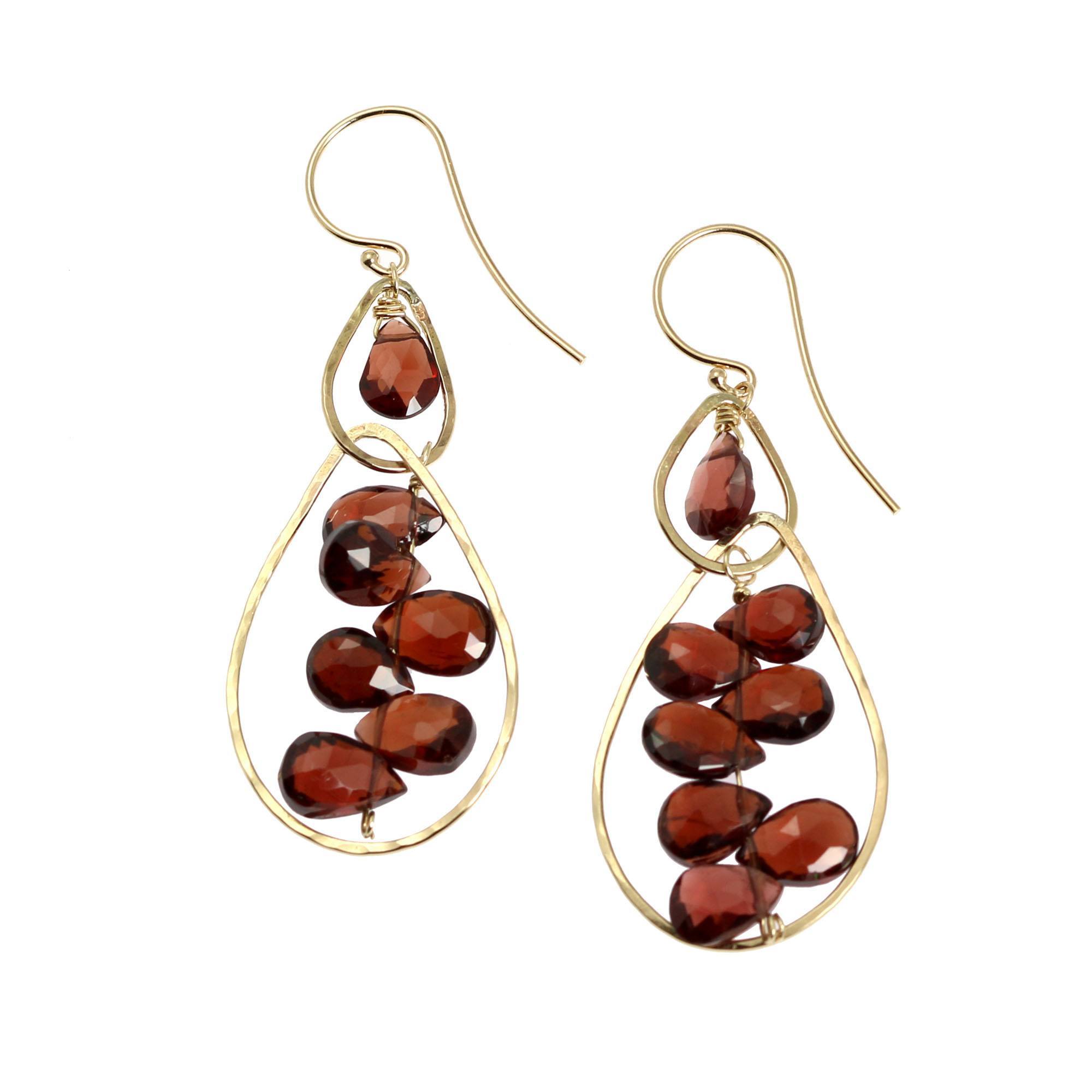 A Pair of 14K Gold Hammered Earrings With Garnets on a White Background