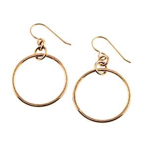 1 of 8: Pair of 1 inch hammered bronze hoop earrings displayed on a clean white background. The round bronze hoops have a glossy polished finish with subtle hand hammered texture and hang from bronze French ear wires through small connecting rings.