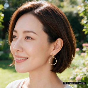 2 of 8: AI generated female model with short dark brown hair wearing a 1 inch hammered bronze hoop earring outdoors in soft natural light. The polished bronze hoop hangs from a French ear wire and is clearly visible against her hair and skin, showing the earring's size and warm color when worn.