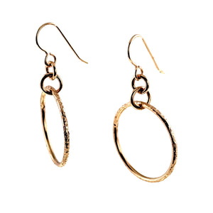 3 of 8: Pair of 1 Inch Texturized Rim Bronze Hoop Earrings shown at an angle on a white background. Each earring has a warm polished bronze finish, a hand textured hoop rim, connecting rings, and a curved bronze French ear wire.