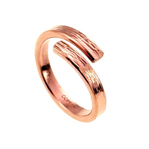 1 of 9: Three quarter view of a slim bark textured copper bypass ring on a white background. The open ends overlap slightly at the front, showing the raised natural texture, polished inner band, warm reddish copper tone, and stamped copper marking inside.