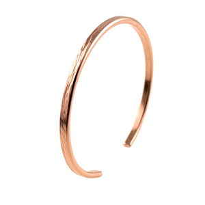 8 of 10: A high-resolution image of a handcrafted 3.5mm wide copper cuff bracelet with an open-ended design, displayed at an angle against a plain white background. The bracelet features a lightly embossed bark texture along its outer surface, adding a natural, organic look to its sleek and polished finish. The raw, non-oxidized copper has a warm reddish tone that subtly reflects light. The curved ends are softly rounded for comfort, showcasing the bracelet’s minimal and refined shape, suitable for everyday wear.
