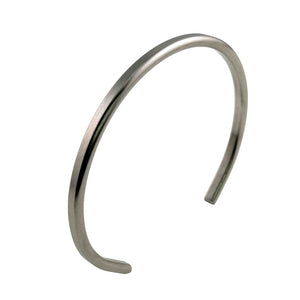 7 of 10: Angled side view of a 3.5mm brushed stainless steel cuff bracelet on a white background. The slim open cuff shows its rounded rectangular profile, matte silver tone surface, curved shape, and softly finished ends.