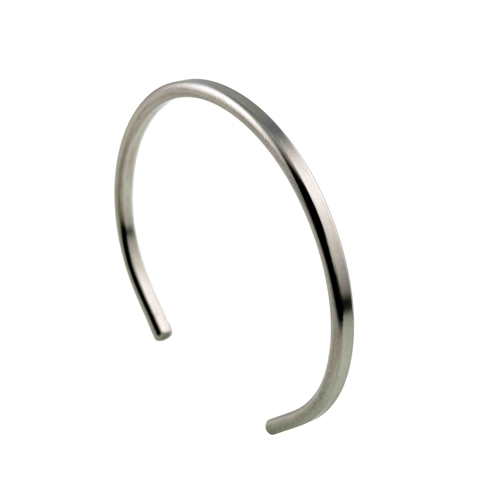 Alternate angled view of a slim brushed stainless steel cuff bracelet against a white background. The open cuff is shown from the opposite side, highlighting its narrow 3.5mm width, smooth curves, matte finish, and rounded ends.