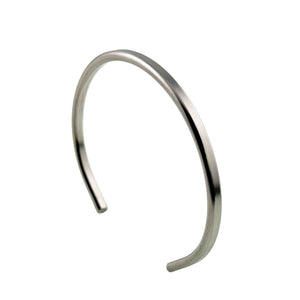 1 of 10: Alternate angled view of a slim brushed stainless steel cuff bracelet against a white background. The open cuff is shown from the opposite side, highlighting its narrow 3.5mm width, smooth curves, matte finish, and rounded ends.