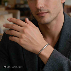 9 of 10: AI generated male model wearing a slim brushed stainless steel cuff bracelet with a dark charcoal blazer. The close view focuses on his hand and wrist, showing the narrow silver tone bracelet as a clean accessory for dressier casual clothing.