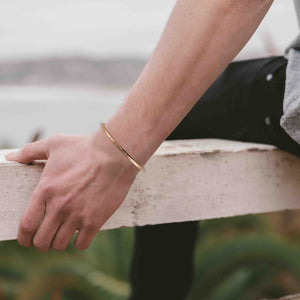 6 of 9: Person wearing a 3.5mm Chased Bronze Cuff Bracelet  on a blurred natural background