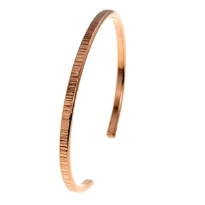 10 of 11: A slim, handcrafted copper cuff bracelet with a 3.5mm width and vertical chased texture, shown standing upright against a white background in an open-ended design.