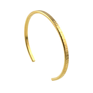 1 of 9: Thin handcrafted cuff bracelet made of solid Nu Gold brass with a subtle chased texture along the surface, giving it a lightly ridged, reflective finish. The bracelet has a slim 3.5mm width and an open-ended design for easy wearing. Its warm golden hue resembles polished gold, while the minimal and elegant shape makes it versatile for everyday or special occasion wear. Shown against a white background.