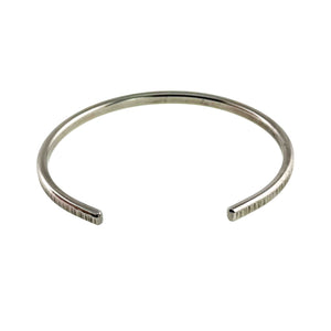 3 of 11: Front angled product photograph of the John S. Brana 3.5mm Chased Stainless Steel Cuff Bracelet against a white background. The open cuff design shows two smooth, rounded ends separated by a gap for sliding the bracelet onto the wrist. Hand chased vertical marks decorate the outer surface of the silver tone 316L surgical stainless steel, while the inner surface appears smooth and polished.