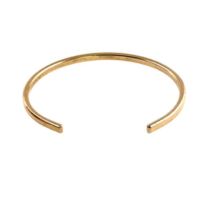 3 of 10: Studio product image of a slim solid bronze cuff bracelet shown against a light gray background. The bracelet features a narrow 3.5mm width with a subtle hand-hammered texture along the outer surface. Its open cuff design has smoothly rounded ends and a gently curved shape for easy wear. The warm golden bronze finish is raw and unoxidized, giving it a soft, natural shine and minimalist modern look.