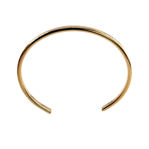 5 of 10: Studio product image of a slim solid bronze cuff bracelet displayed against a light gray background. The bracelet features a narrow 3.5mm width with a smooth, lightly hammered outer surface that reflects light subtly. Its open cuff design has gently rounded ends and a clean, curved shape for comfortable wear. The warm golden bronze finish is raw and unoxidized, giving it a simple, modern, and minimalist look.