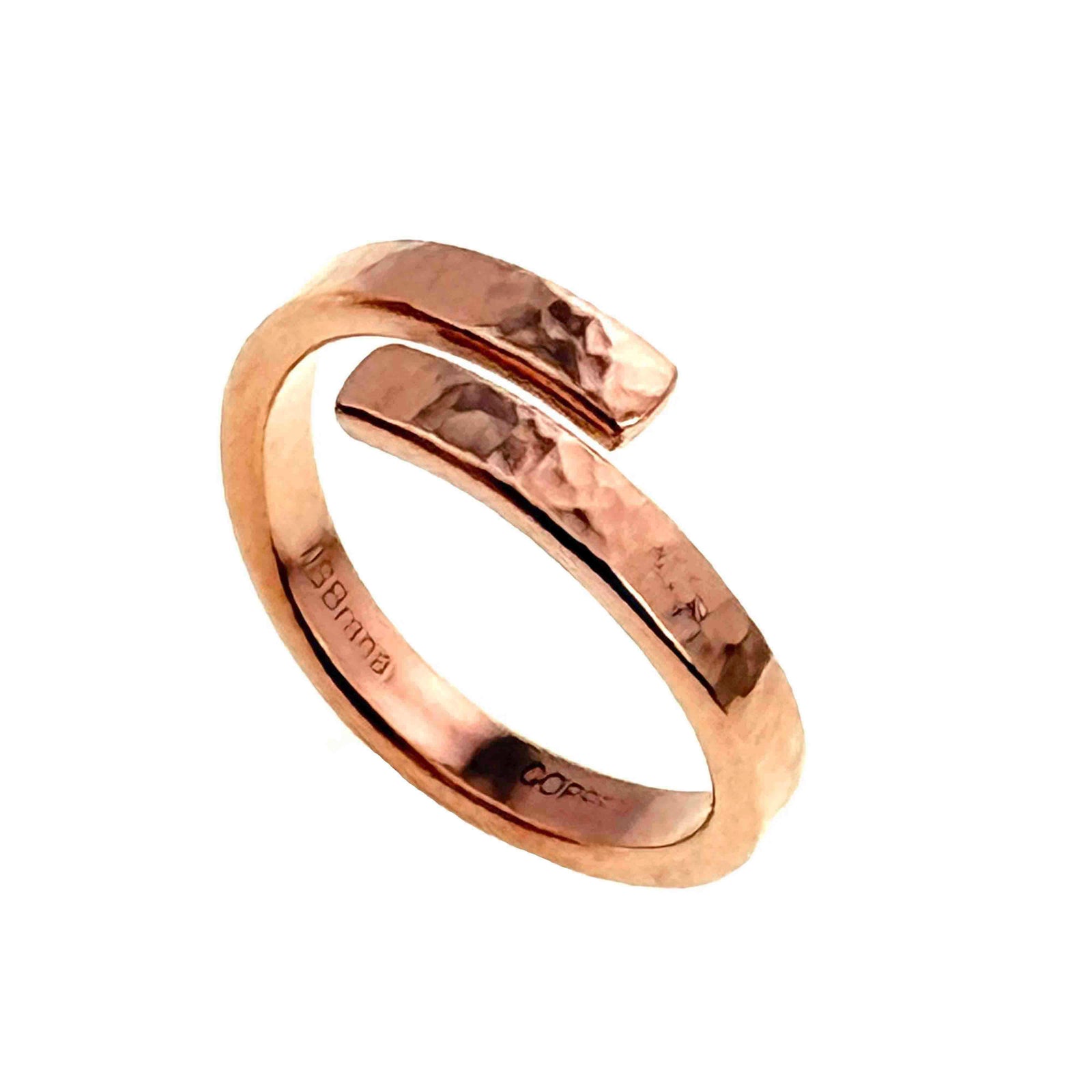A handcrafted, polished 3.5mm copper bypass ring with a hammered texture. The ring features an open front design where the two ends curve past each other without touching, creating a modern wrap-around style. The surface is shiny with visible hammered marks, adding depth and character. The inner band is stamped with "J S Brana" and "Copper," indicating the designer and metal type. The ring has a warm reddish-brown hue, typical of raw, uncoated copper.