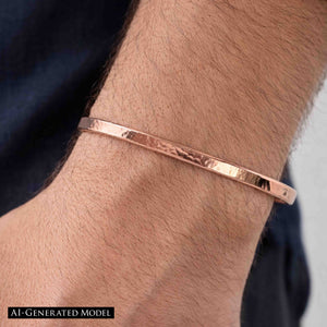 4 of 9: Close-up of a man wearing a 3.5mm hand-hammered copper cuff bracelet on his wrist. The bracelet has a warm, polished copper finish with a textured surface that reflects light. Its slim, open-ended design curves gently around the wrist for a comfortable fit. The person is wearing a dark blue shirt, and the bracelet stands out against their skin tone, highlighting its handcrafted, minimalist style.  AI Generated Model.