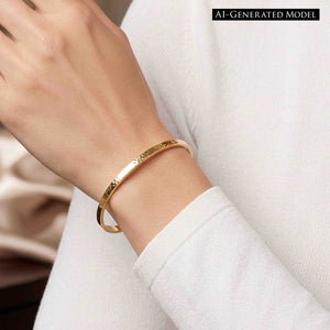 8 of 10: Close-up of a woman wearing a slim hammered Nu Gold brass cuff bracelet on her wrist, styled with a soft white long sleeve top. The narrow 3.5mm cuff has a lightly textured surface that reflects warm golden tones. Her hand is gently raised, showing a clean, minimal look in a relaxed indoor setting with soft, neutral background details.  AI Generated Model.