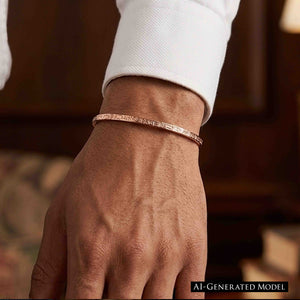 7 of 11: Close-up of a person’s wrist wearing a slim solid copper cuff bracelet with a narrow 3.5mm width and subtle crosshatch linen texture. The open cuff sits comfortably on the wrist, paired with a crisp white shirt sleeve, against a softly blurred warm-toned indoor background.  AI Generated Model.