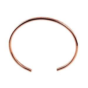 9 of 11: Slim solid copper cuff bracelet with a narrow 3.5mm width, featuring a subtle hand-applied crosshatch linen texture along the outer edge. The open cuff design has smooth rounded ends and a warm polished copper finish, shown from a top-down view on a clean white background.