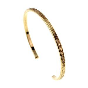 1 of 10: Side profile of the handmade 3.5mm Linen Nu Gold Brass Cuff Bracelet. The narrow solid Nu Gold Brass cuff features a polished interior and hand applied linen texture on the outer edge, showing its lightweight handcrafted construction.