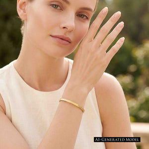 2 of 10: AI generated female model wearing the handmade 3.5mm Linen Nu Gold Brass Cuff Bracelet with a sleeveless cream top. The narrow polished Nu Gold Brass cuff features a hand applied linen texture and warm golden finish, creating a simple, elegant everyday jewelry look.