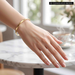 6 of 9: Matte bronze cuff bracelet worn on a woman’s wrist near a marble table and coffee cup. The slim handcrafted bronze bracelet features a brushed satin finish and simple open cuff design that works beautifully with relaxed daytime fashion and layered jewelry looks.  AI Generated Model.