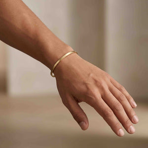 4 of 9: Man wearing a slim 3.5mm matte bronze cuff bracelet on his wrist. The handcrafted bronze cuff has a brushed satin finish and delicate minimalist style that pairs easily with casual and modern outfits. The warm bronze tone adds a soft glow against the skin.