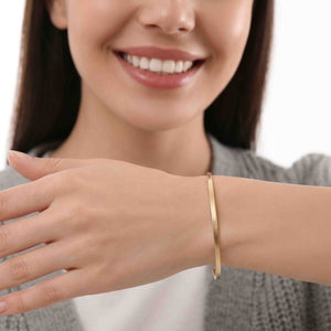 2 of 9: Close up of a smiling woman wearing a 3.5mm matte bronze cuff bracelet. The slim handcrafted bronze bracelet features a smooth brushed finish and minimalist open cuff design that adds subtle warmth and modern elegance to casual everyday outfits.
