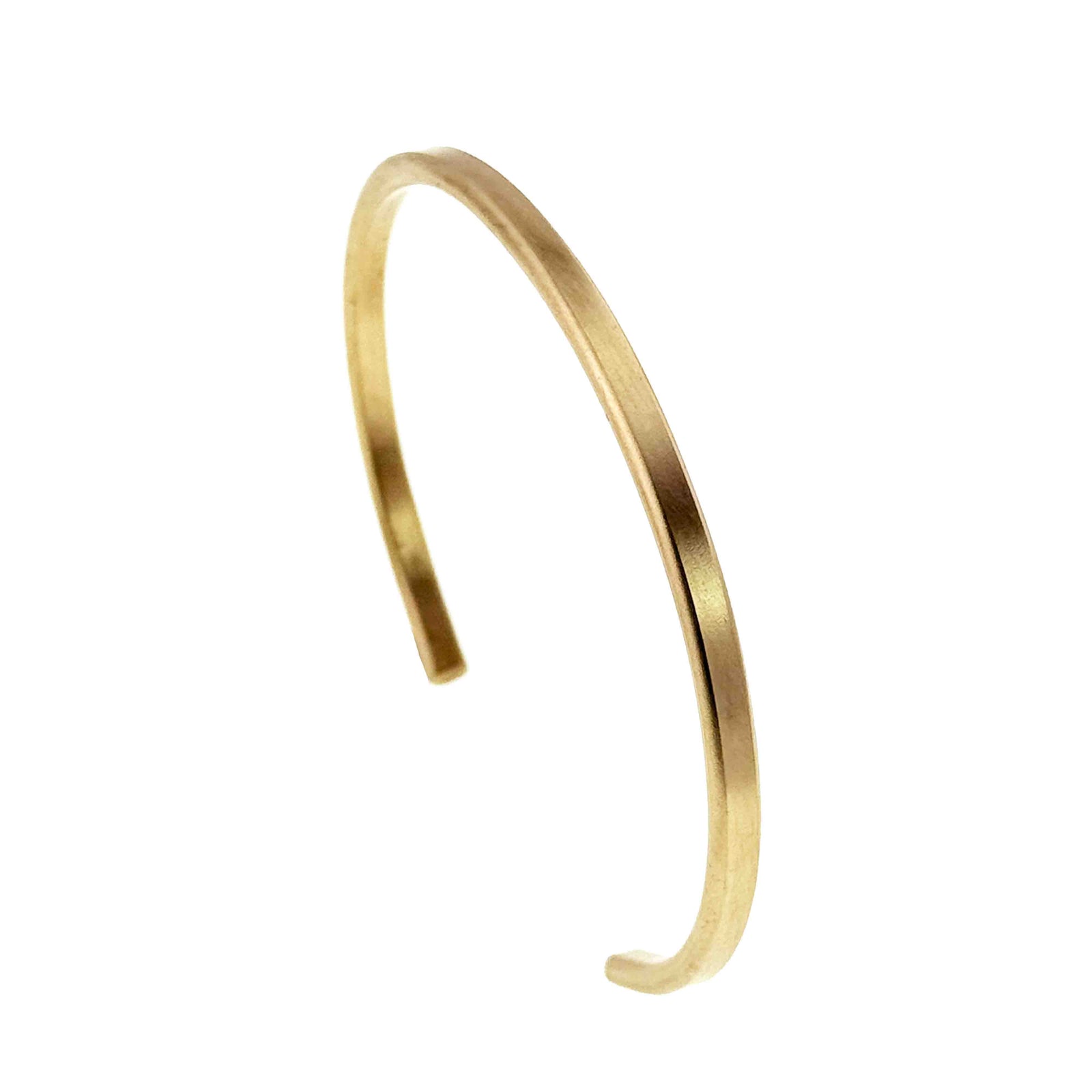 Opposite angled view of the 3.5mm matte Nu Gold brass cuff bracelet on a white background, highlighting the gentle curve, narrow band, warm golden color, and open ends.