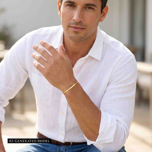 4 of 10: AI generated male model wearing a white shirt and jeans with a narrow matte Nu Gold brass cuff bracelet on his raised wrist in a bright outdoor setting.