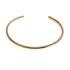 7 of 10: Low front product view of a slim polished bronze cuff bracelet on a white background. The open ends point upward, showing the smooth interior curve, rounded tips, narrow width, and reflective hand polished bronze surface.