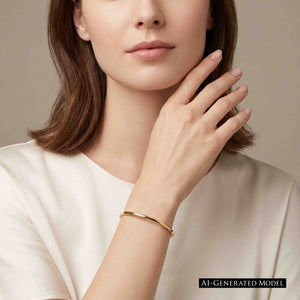 2 of 10: A close cropped woman in an ivory blouse raises one hand near her face while wearing a slim, high polished bronze cuff bracelet. The warm golden bronze band rests just above her wrist and catches the soft studio light. A label reads “AI GENERATED MODEL.”