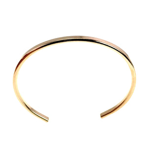 3 of 10: Overhead product view of a slim polished bronze cuff bracelet on a white background. The bracelet forms a rounded open circle with a gap at the bottom, smooth rounded ends, and a bright reflective golden bronze finish.