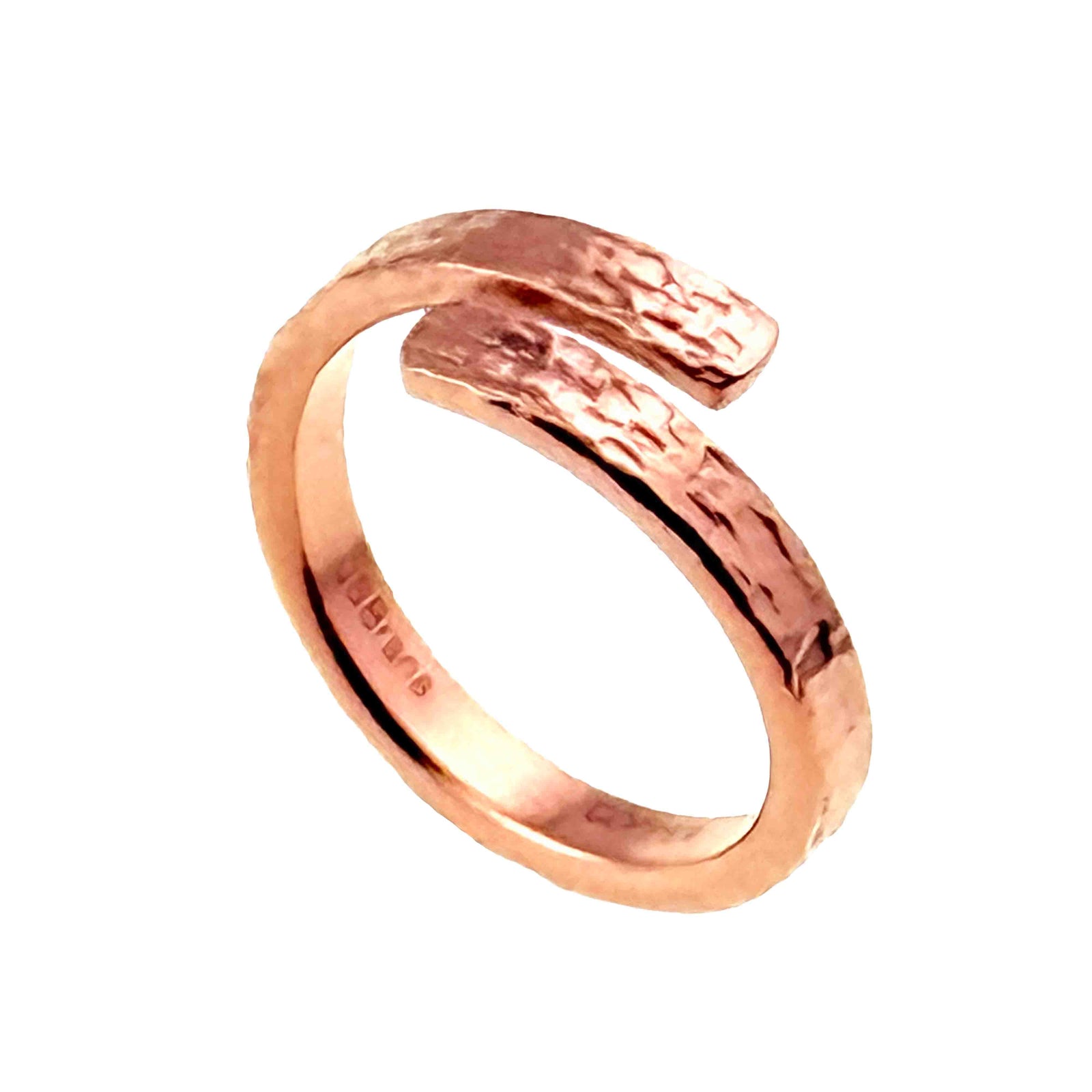 Angled close view of the polished copper bypass ring on a white background. Two rounded ends overlap with an open space between them, showing the hand applied texture across the warm copper surface.