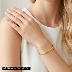 2 of 9: A blonde woman in a sleeveless white top wears a slim texturized Nu Gold brass cuff bracelet. Her hand rests gently on her opposite shoulder while the polished golden cuff circles her wrist, showing its narrow profile, textured outer surface, and open ends in soft neutral lighting.  AI Generated model.