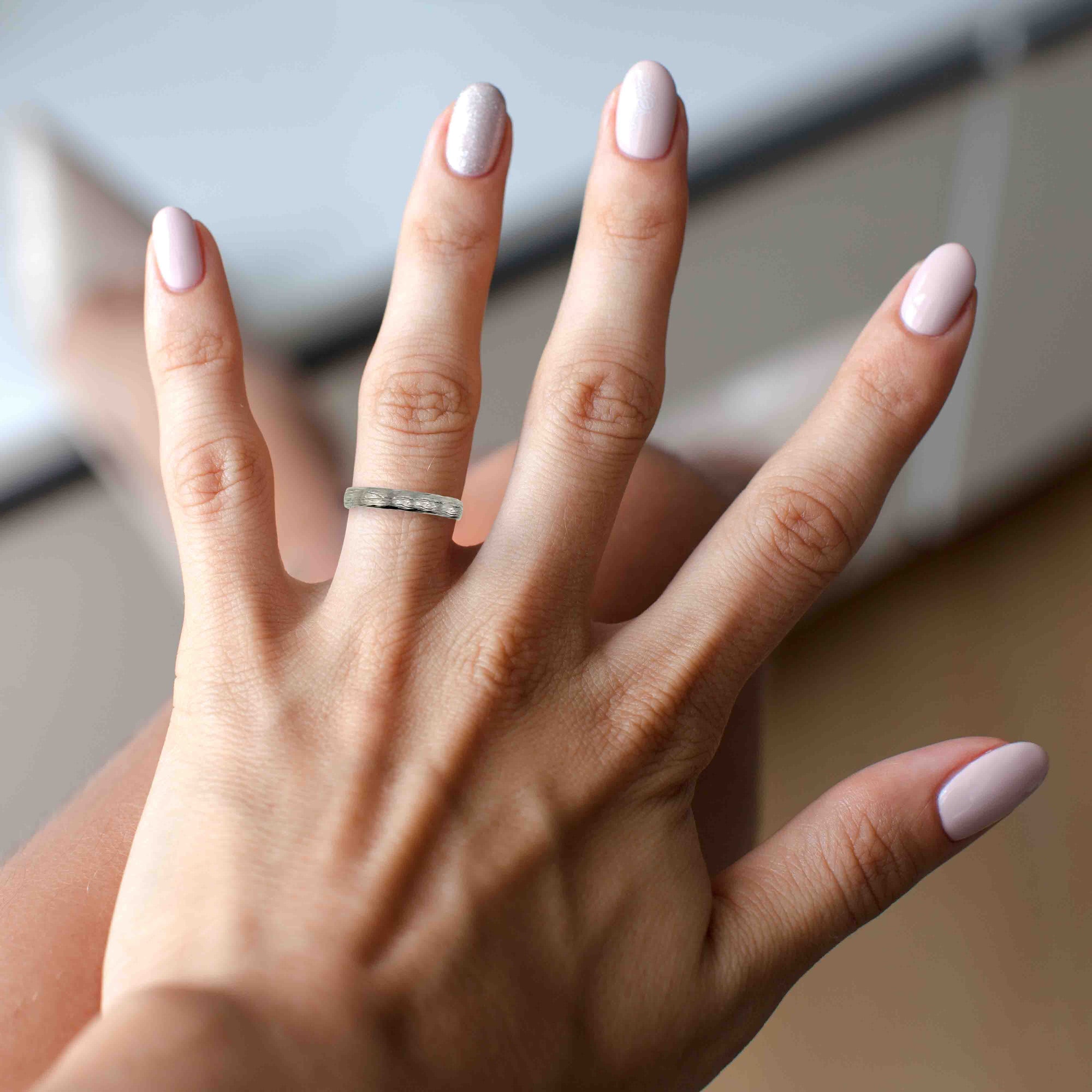 A Woman's Hand with a 3mm Bark Stainless Steel Comfort Fit Ring on a blurred indoor background