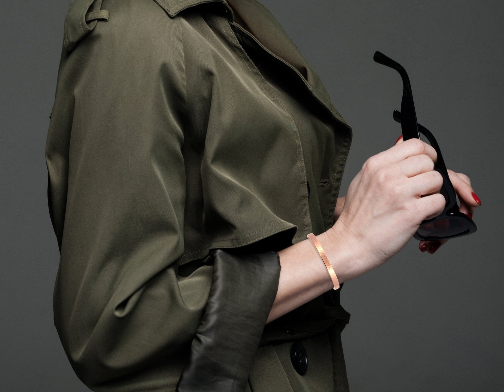 4mm Wide Hammered Copper Cuff Bracelet on Female Wrist Wearing a Green Raincoat