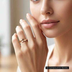 2 of 9: Close up of a woman’s face and hand wearing a slim bronze bypass ring on her finger. The open band wraps around with two flat ends that nearly meet, showing a fine bark texture and warm polished bronze finish. Her hand rests near her cheek in soft natural light, creating an elegant, minimal styling image that highlights the ring’s modern, handcrafted look.  AI Generated Model.