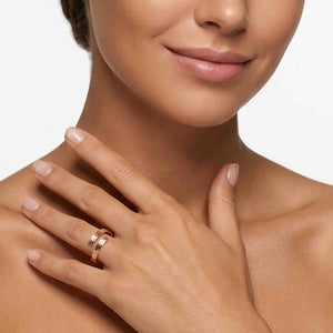 4 of 9: Close up of a woman’s lower face, neck, and hand wearing a slim bronze bypass ring on her ring finger. The open band wraps around with two ends that nearly meet, showing a soft bark texture and warm polished bronze shine. Her hand rests gently on her shoulder against a clean light background, giving the ring an elegant, modern look.