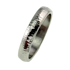 5 of 9: Upright side view of a 4mm chased stainless steel domed ring on a white background. The slim polished band displays hand worked marks across its curved outer face, bright silver reflections, darker mirrored areas, and a smooth flat interior.
