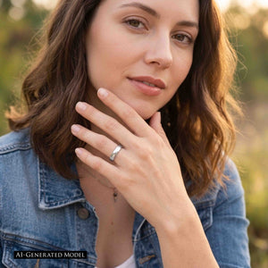 4 of 9: Outdoor portrait of a woman in a denim jacket wearing a slim chased stainless steel domed ring on her ring finger. Her hand rests near her chin as warm sunlight highlights the polished silver band and its hand worked texture. The image includes an AI generated model label.