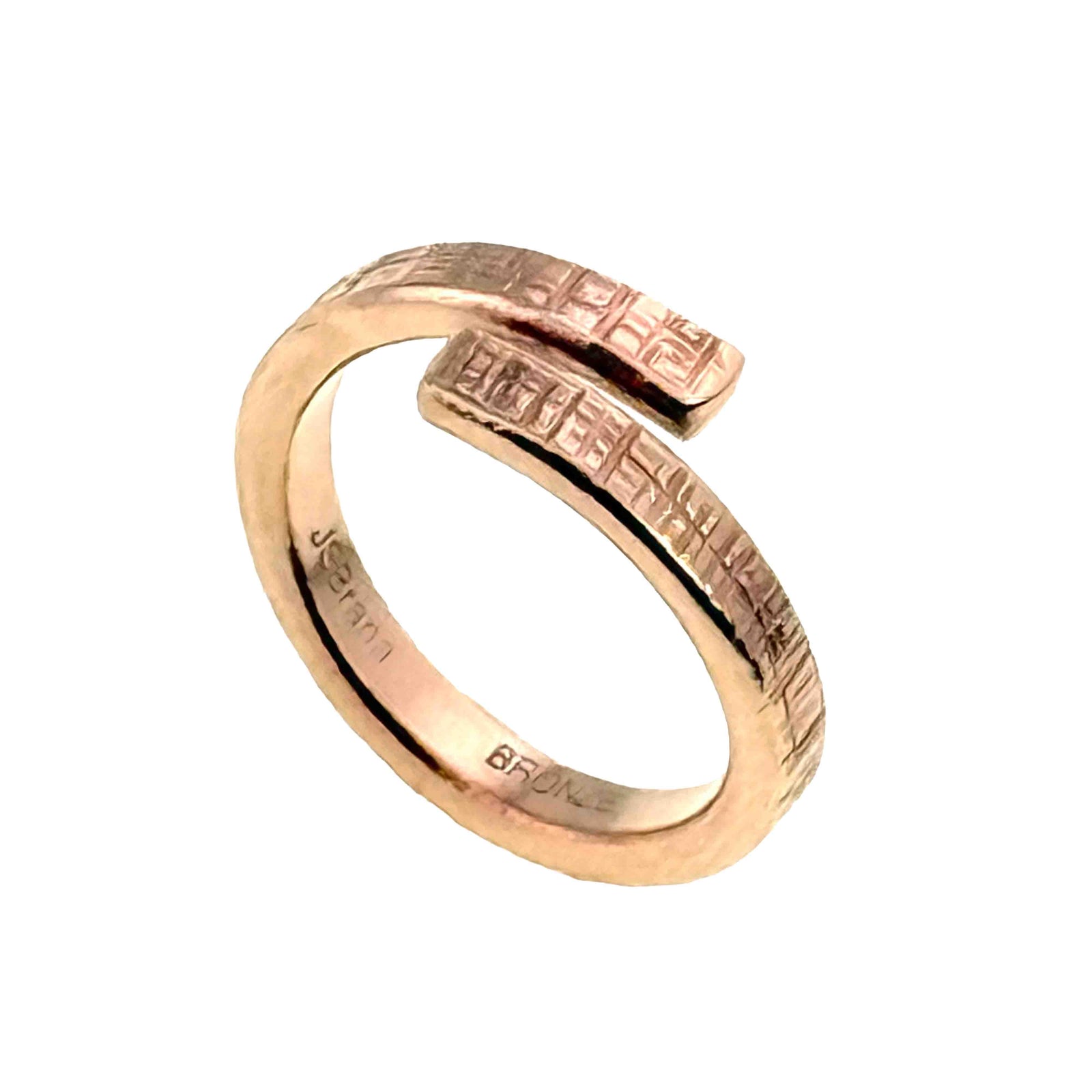 Handmade 4mm Linen Bronze Bypass Ring featuring a hand-applied linen texture with a raw, uncoated bronze finish. The open-ended wrap design showcases a clean, modern silhouette with a rustic, artisanal feel. Crafted from 92% copper and 8% tin, this unisex ring is ideal for everyday wear or as a meaningful 8th anniversary gift. Inner band engraved with "BRONZE" and the artist’s signature "JSBrana."
